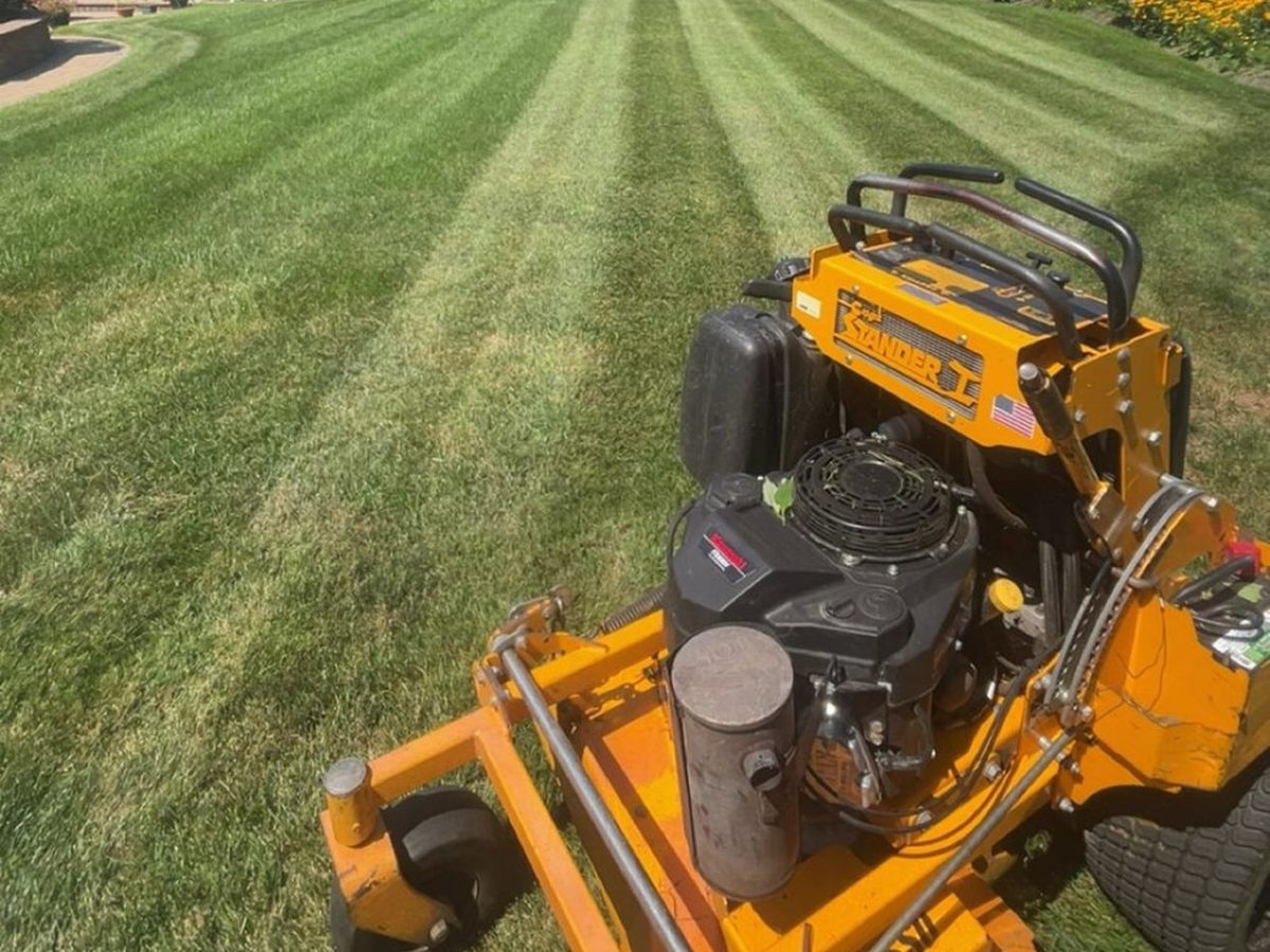 Commercial stand-on mower striping a Long Island lawn