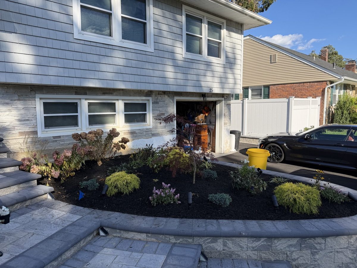 Curved front planter bed finished with fresh black mulch and plantings