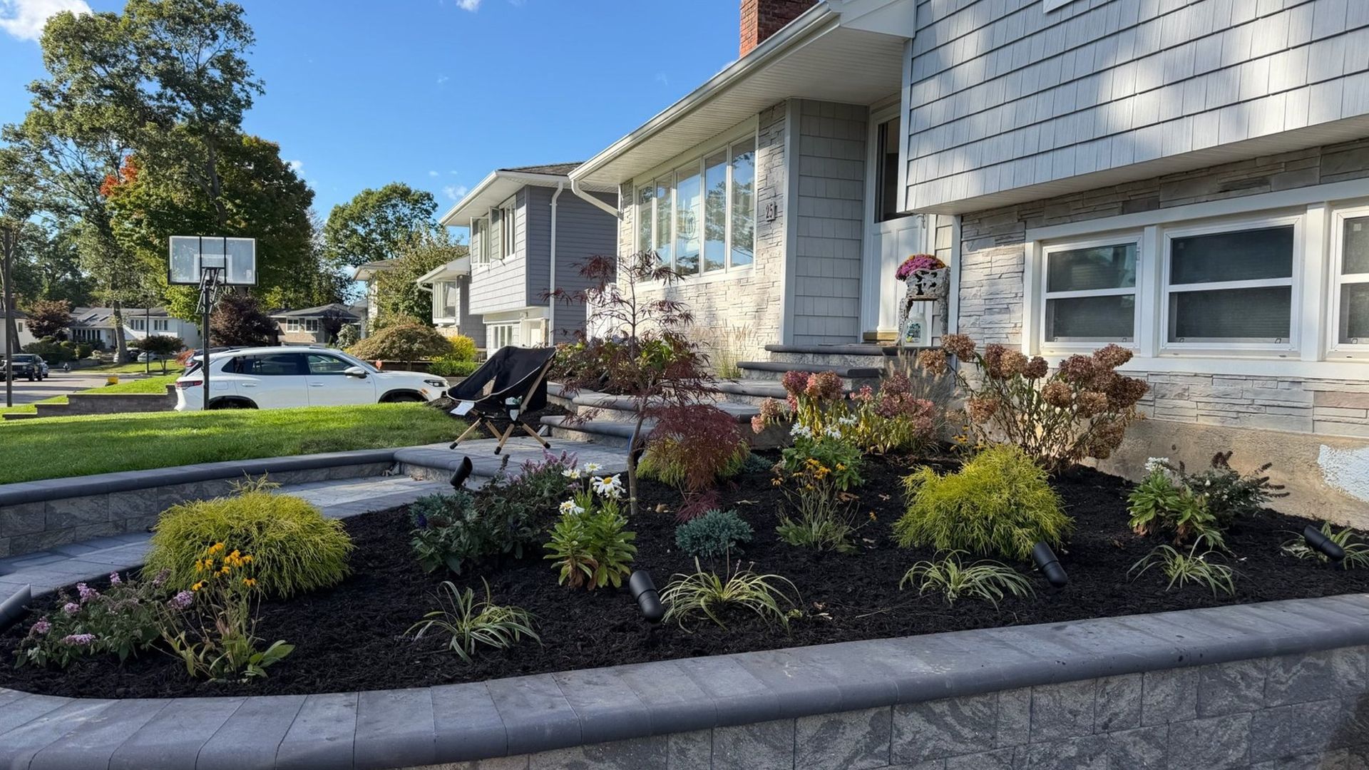 Fresh mulch bed with new plantings behind a stone wall